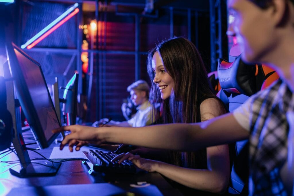 Group of teenagers happily engaged in gaming at a computer setup indoors.