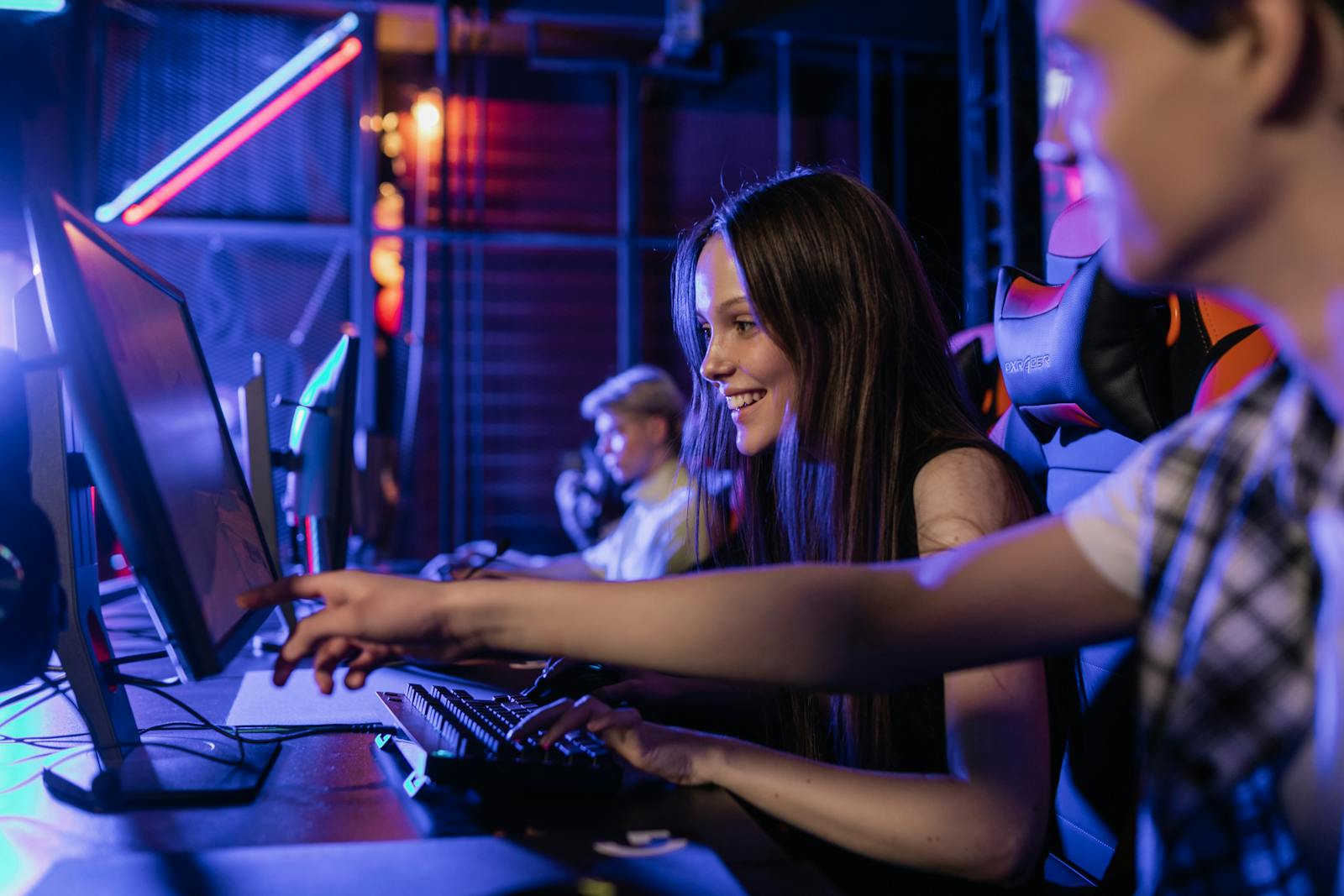 Group of teenagers happily engaged in gaming at a computer setup indoors.